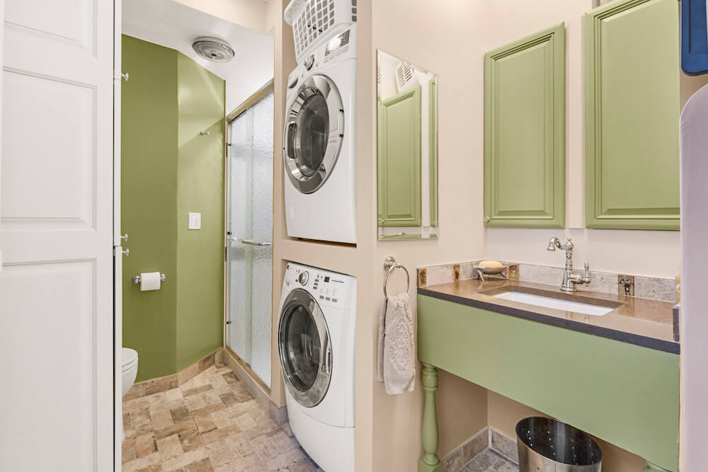 Stacked washer dryer next to inbuilt sink and vanity and white storage cabinet after renovation
