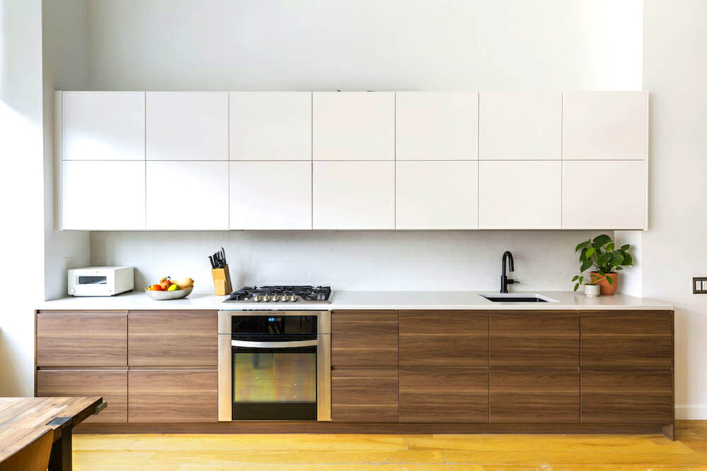 maple kitchen cabinets and white countertop and gas cooking range with oven and white overhead cabinets and open to dining after renovation