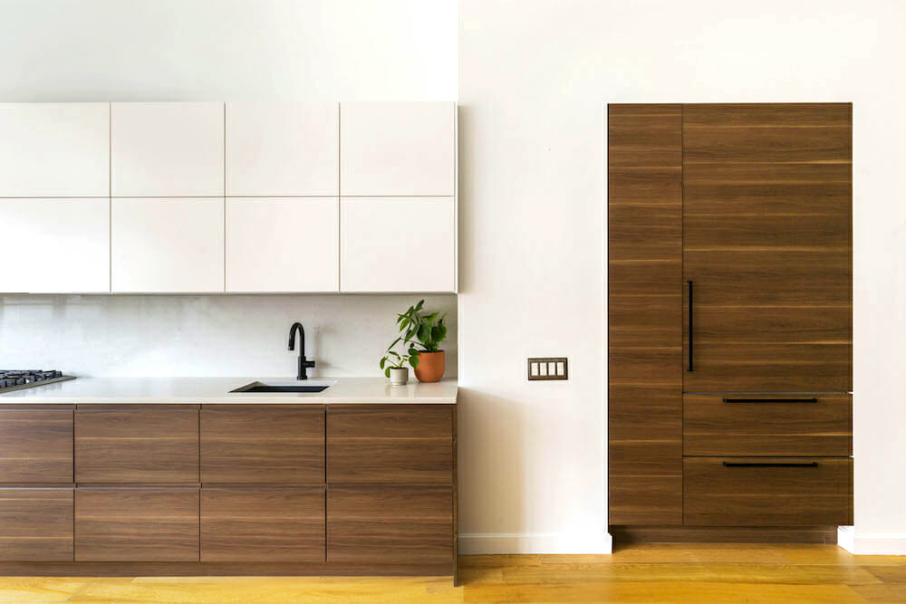 custom maple or natural wood under counter cabinets and marble countertop with undermount sink and black faucet and white overhead cabinets and hardwood flooring after renovation