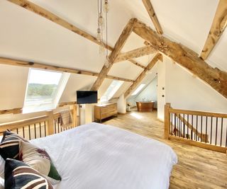 Open plan loft conversion with beamed ceiling, double bed and copper bath