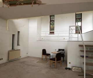 Inside a renovation with a stairway leading to a mezzanine and a small seating area