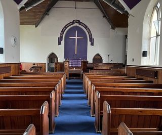 Inside a church with wooden pews and an alter