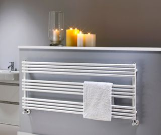 white horizontal tubed towel rail on grey wall in bathroom