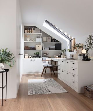 loft conversion home office with white fitted furniture and pale engineered flooring