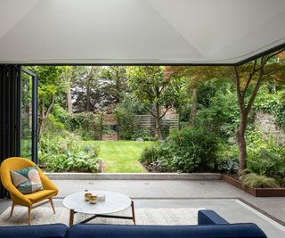 view outside from living room extension with bifold doors open showing full access onto the garden