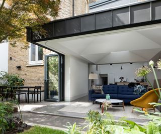 modern living room extension idea with cantilevered ceiling and bifold doors which open on all sides to leave the living room fully open to the outdoors