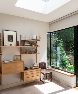 corner of living room extension with wrap around window, window seat, light well in ceiling and shelving unit on wall