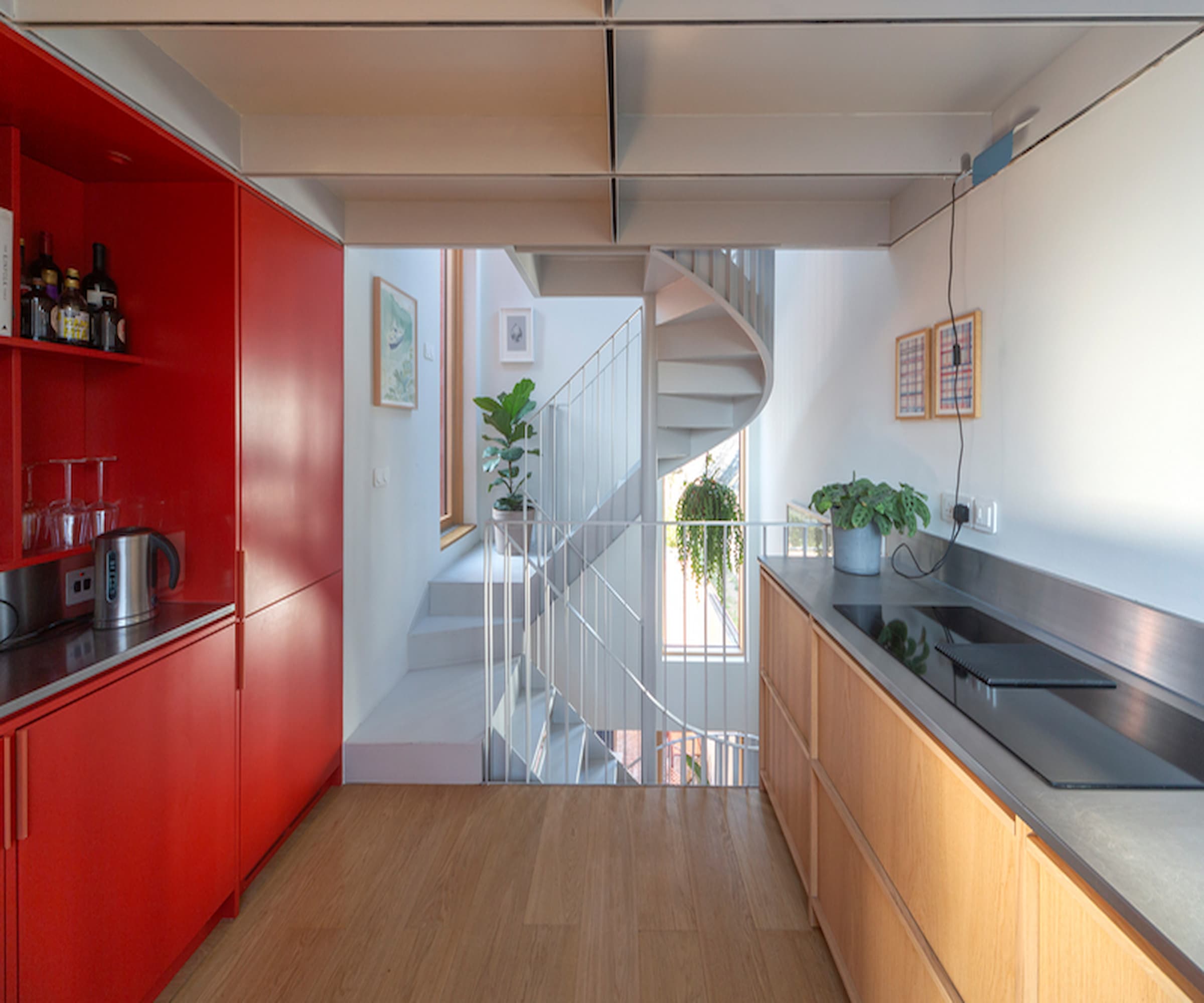 A white staircase linking a top floor red kitchen with the rest of a house