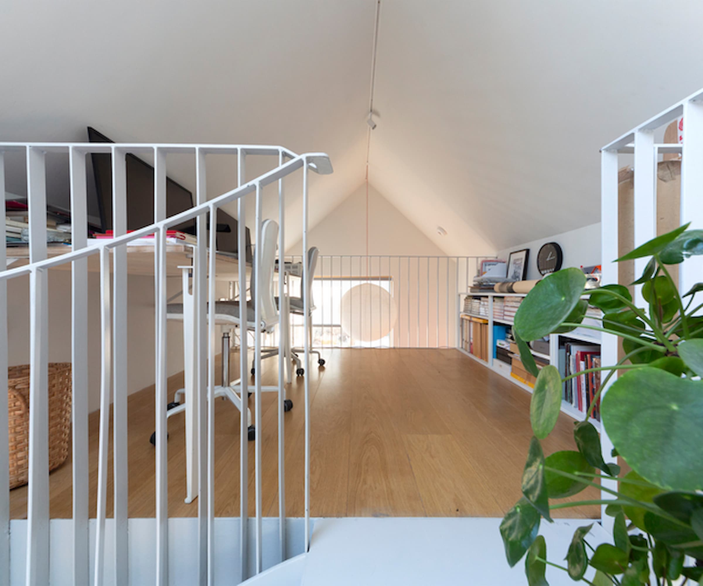 A mezzanine at the top of a house with a vaulted ceiling and two office spaces