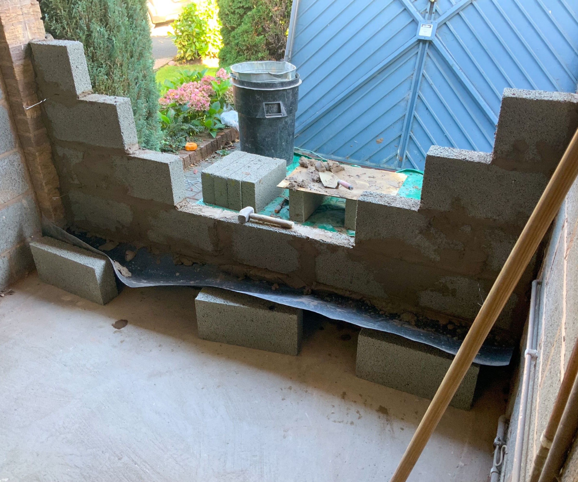 A garage door being bricked up with breeze blocks
