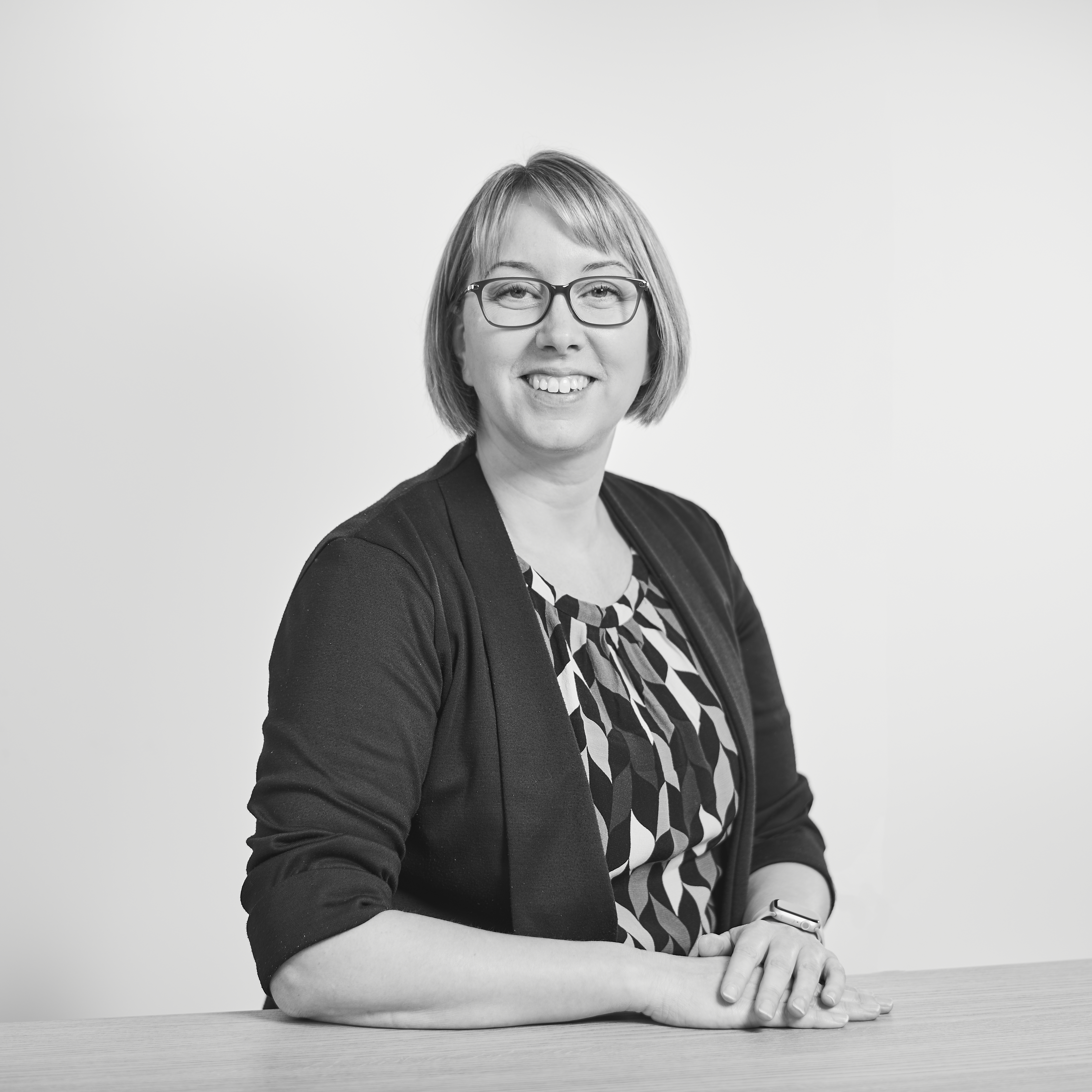 A black and white image of a woman with glasses and a bob