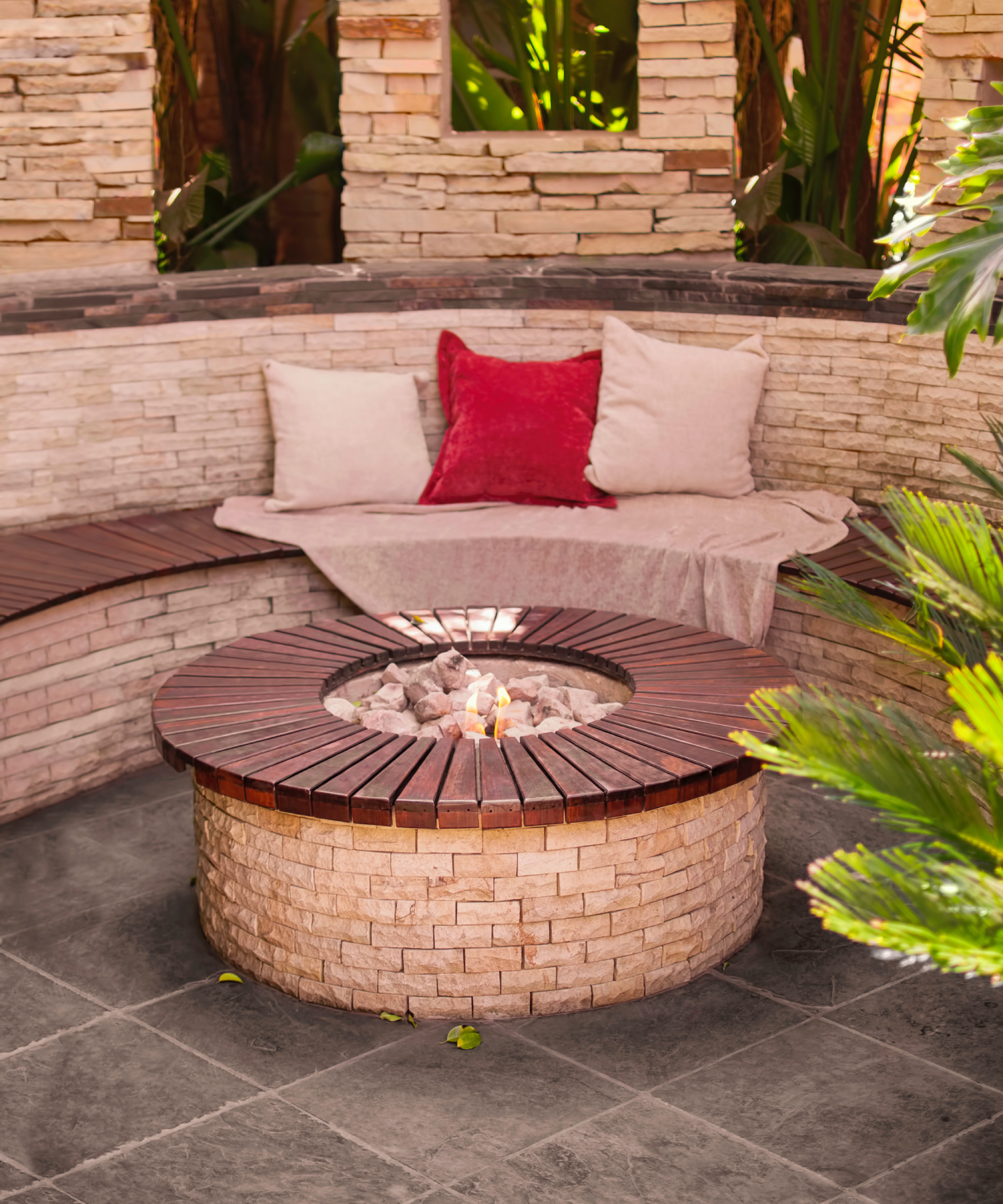buff brick round fire pit with curved seating area and walls made from same materials