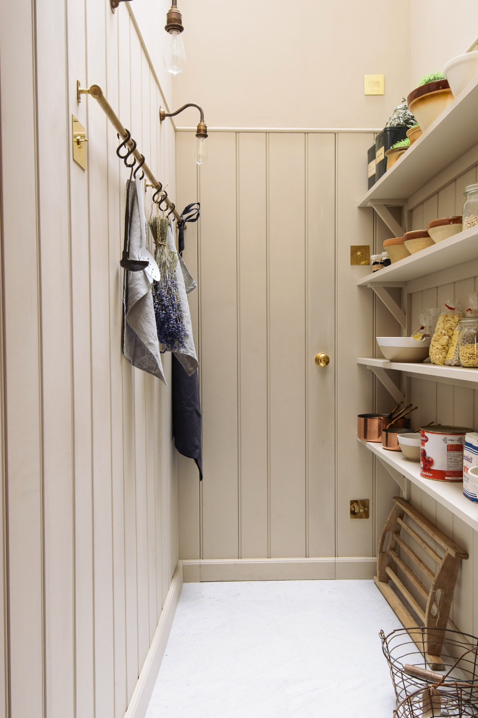 A walk in pantry space with a wood panelled door