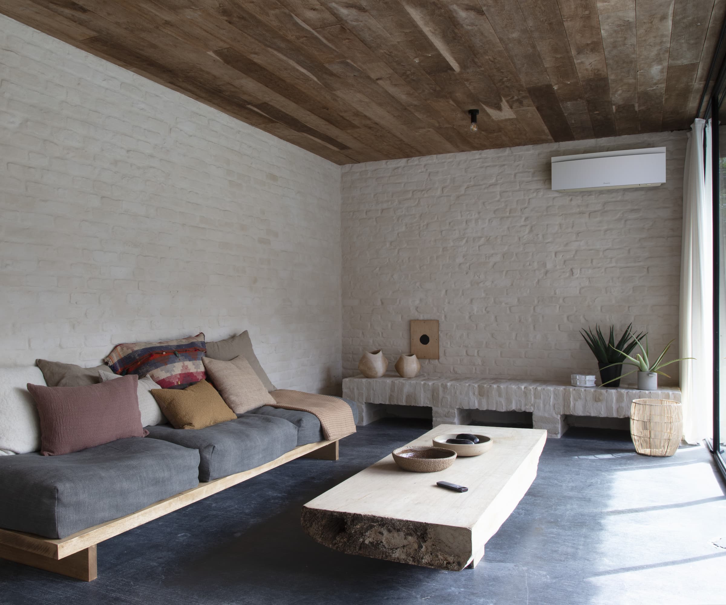 An air conditioning unit on a white wall with a wooden panel roof in a living room
