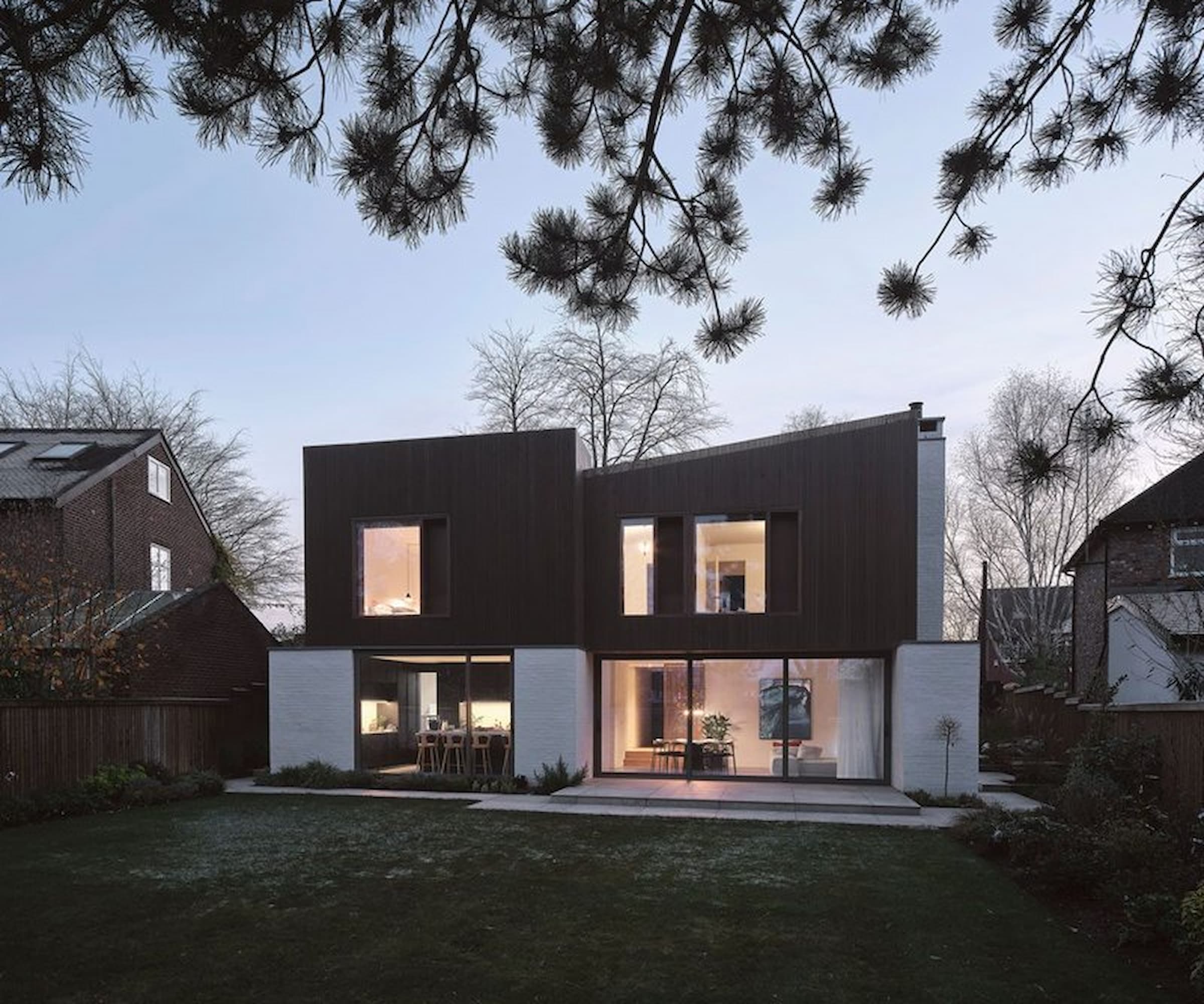 A self build in the rear garden at night with an angled roof and bifold windows