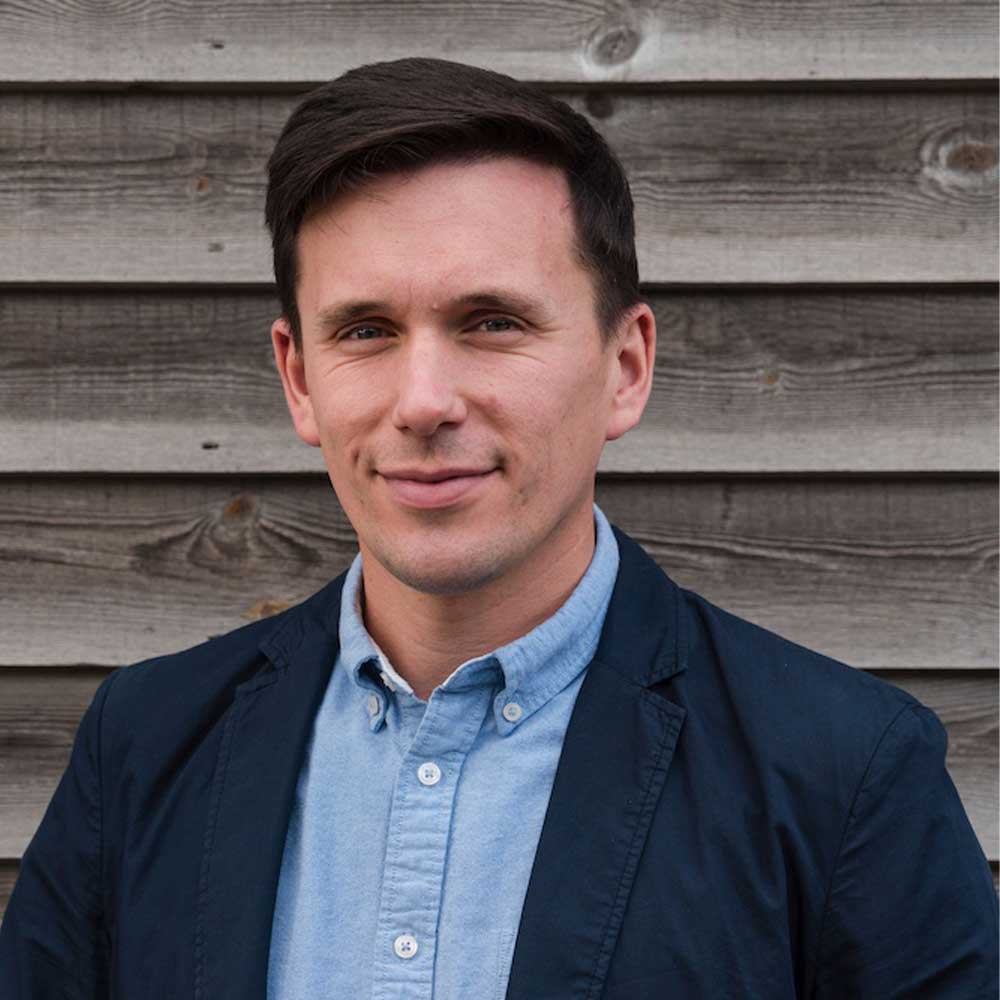 headshot of architect Simon Drayson a man with dark hair wearing a casual suit