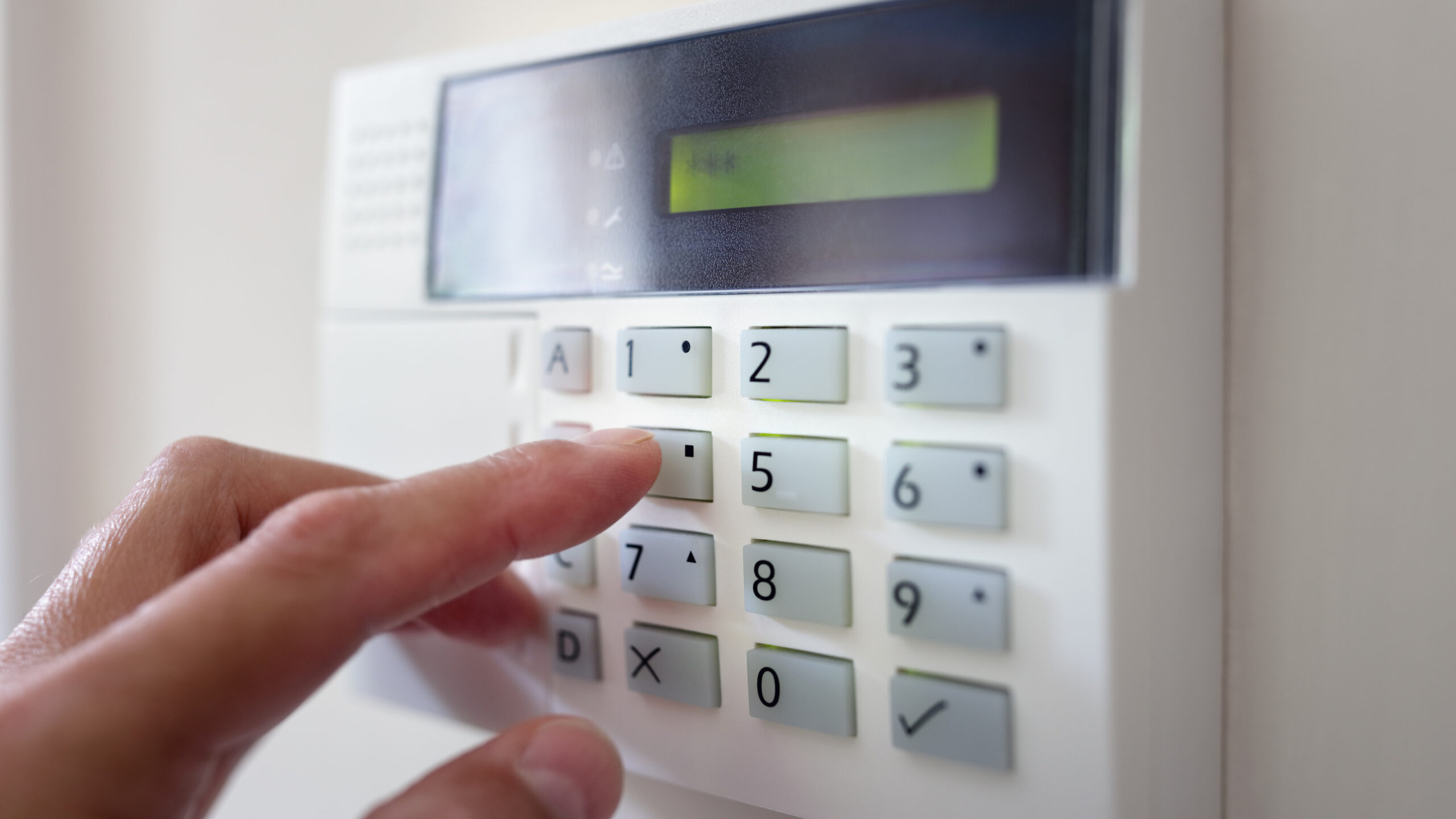 Hand punching numbers on security alarm keypad