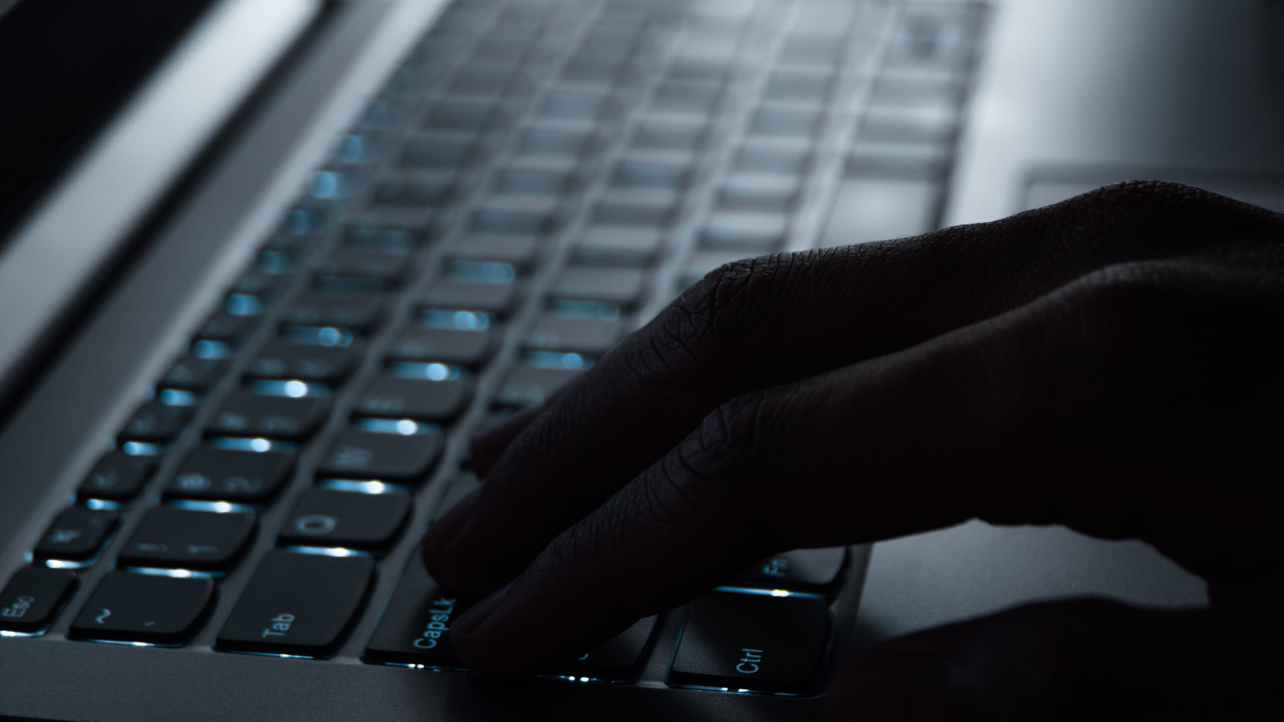 Close up of laptop keyboard with shadowy hand on keys