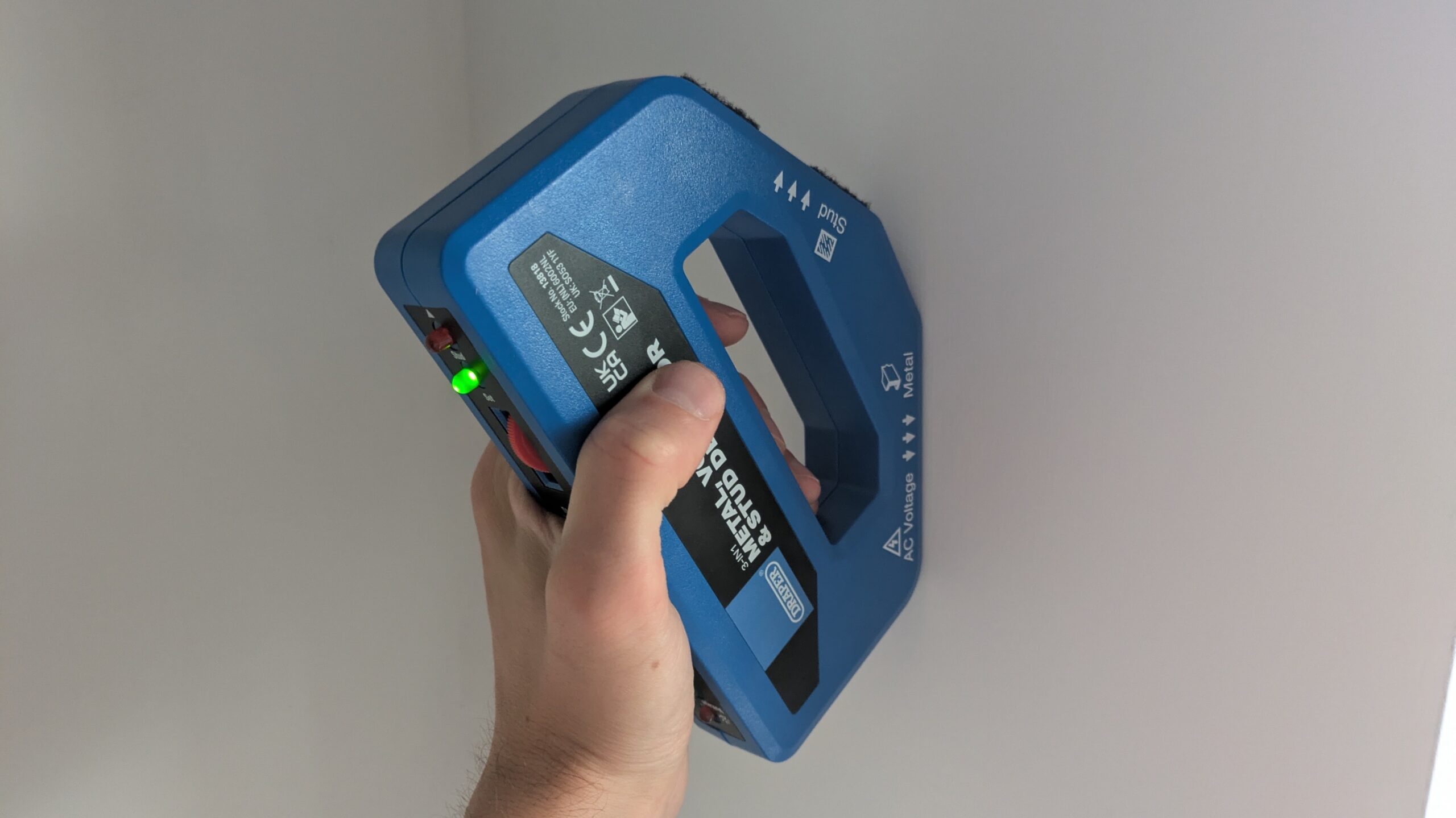 A wire detector being used on a wall