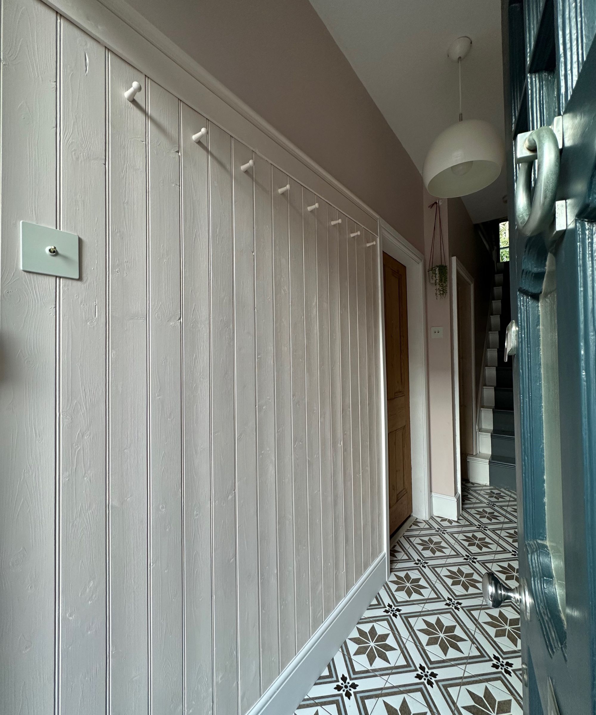 Charming hallway with blush-painted panelling, star-patterned tiles and a row of peg hooks, offering a neat and welcoming first impression.