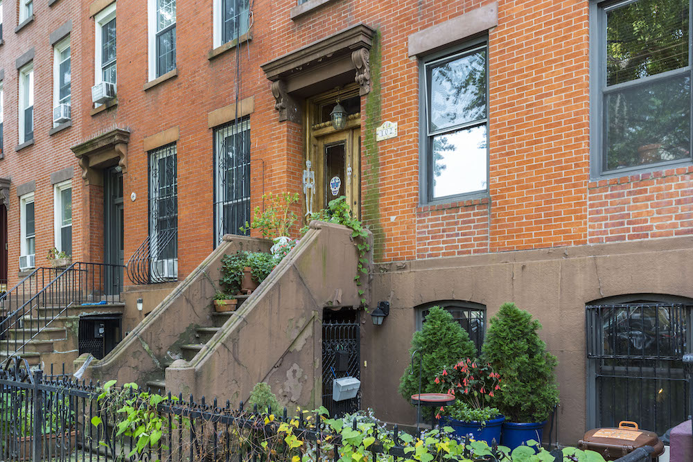 row houses or condominiums with stairs to the entrance and metal fence and brick exterior after renovation