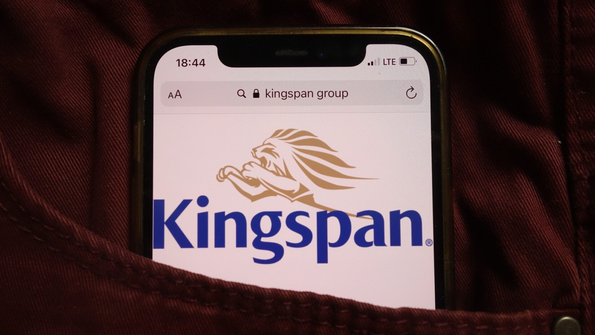Kingspan Group plc logo displayed on mobile phone hidden in jeans pocket - The Competition and Markets Authority has cleared Kingspan