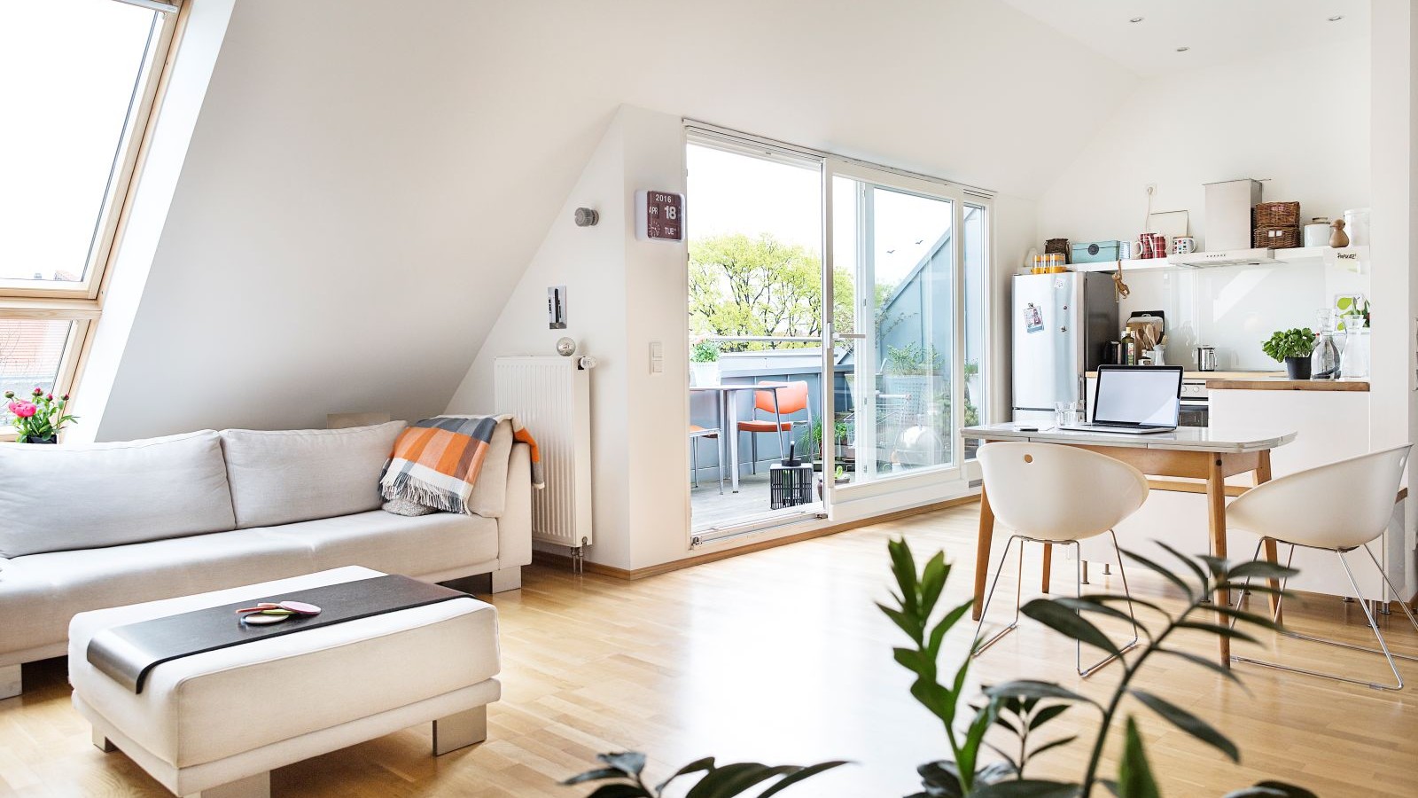 A loft conversion for a living space with sliding glazed doors out to a balcony and a sloped window