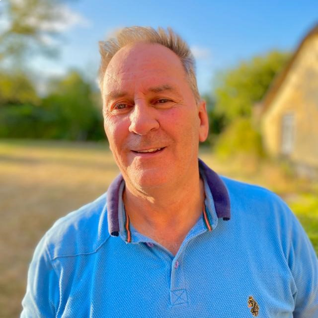 man with short grey hair wearing sky blue polo shirt stood outside