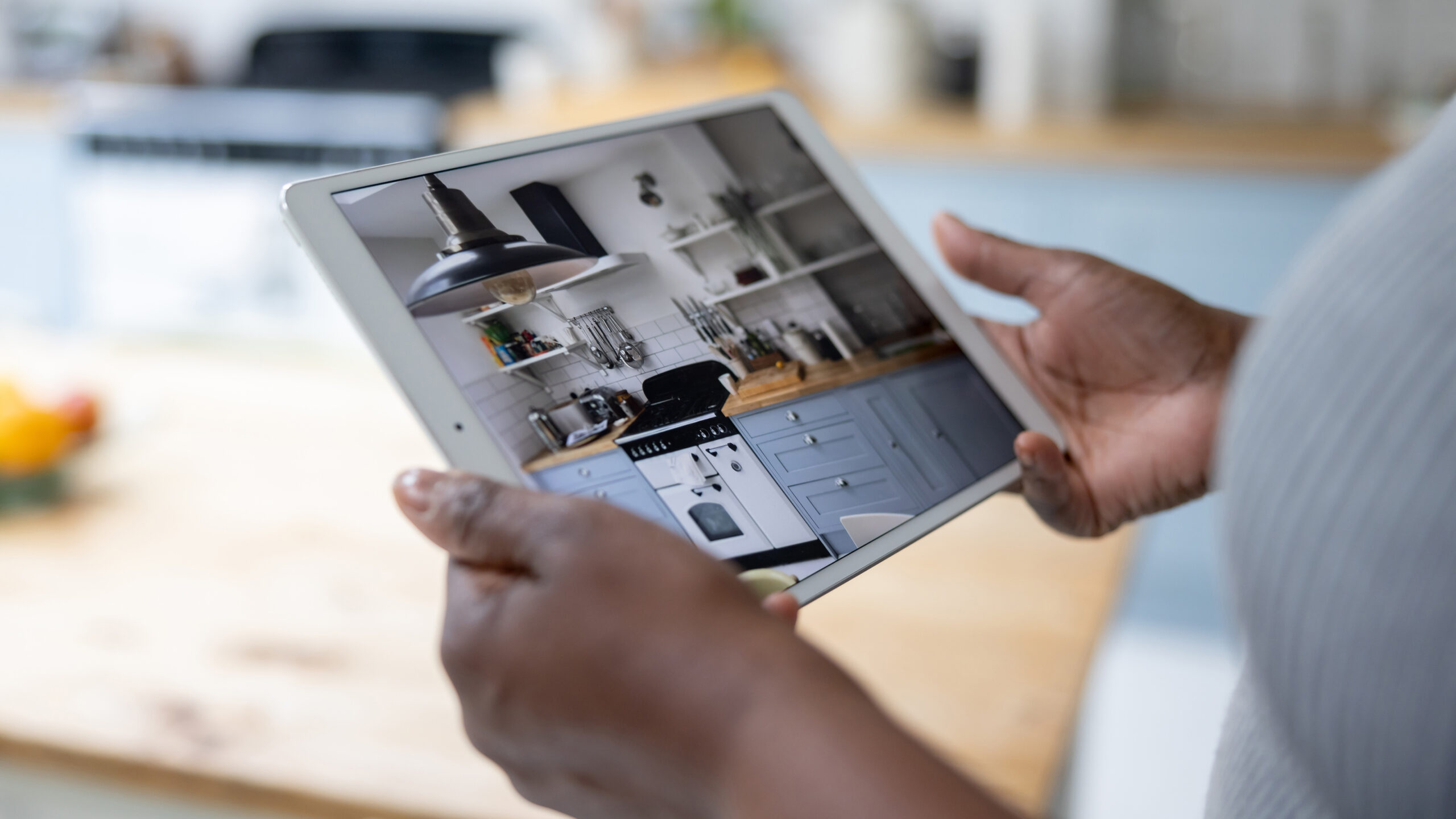 Close-up of a woman holding a tablet and watching her kitchen through a security camera