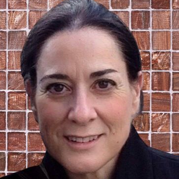 woman with dark hair pulled back off her face smiling at camera