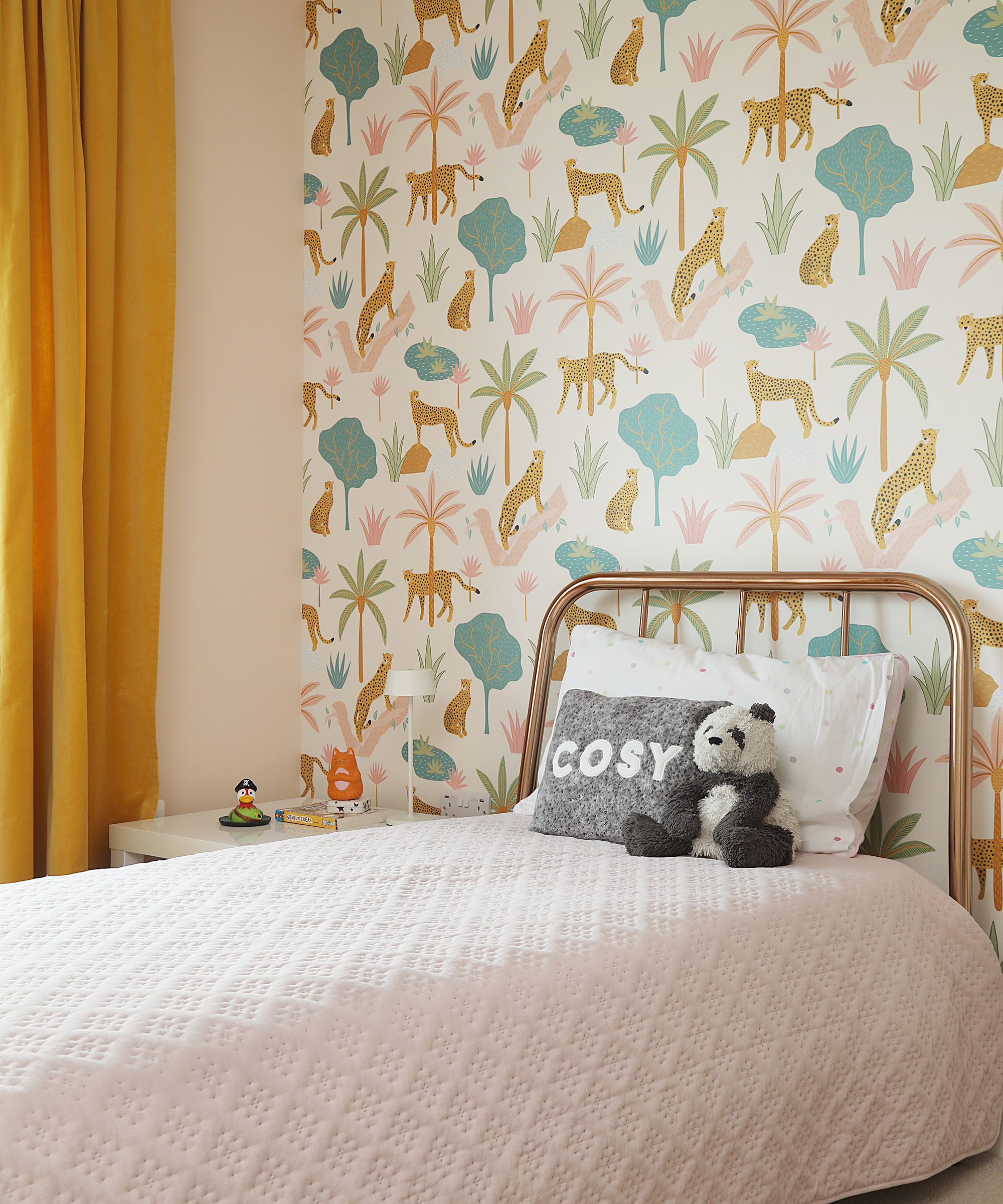 A single bed with metal frame in a child's bedroom with animal wallpaper