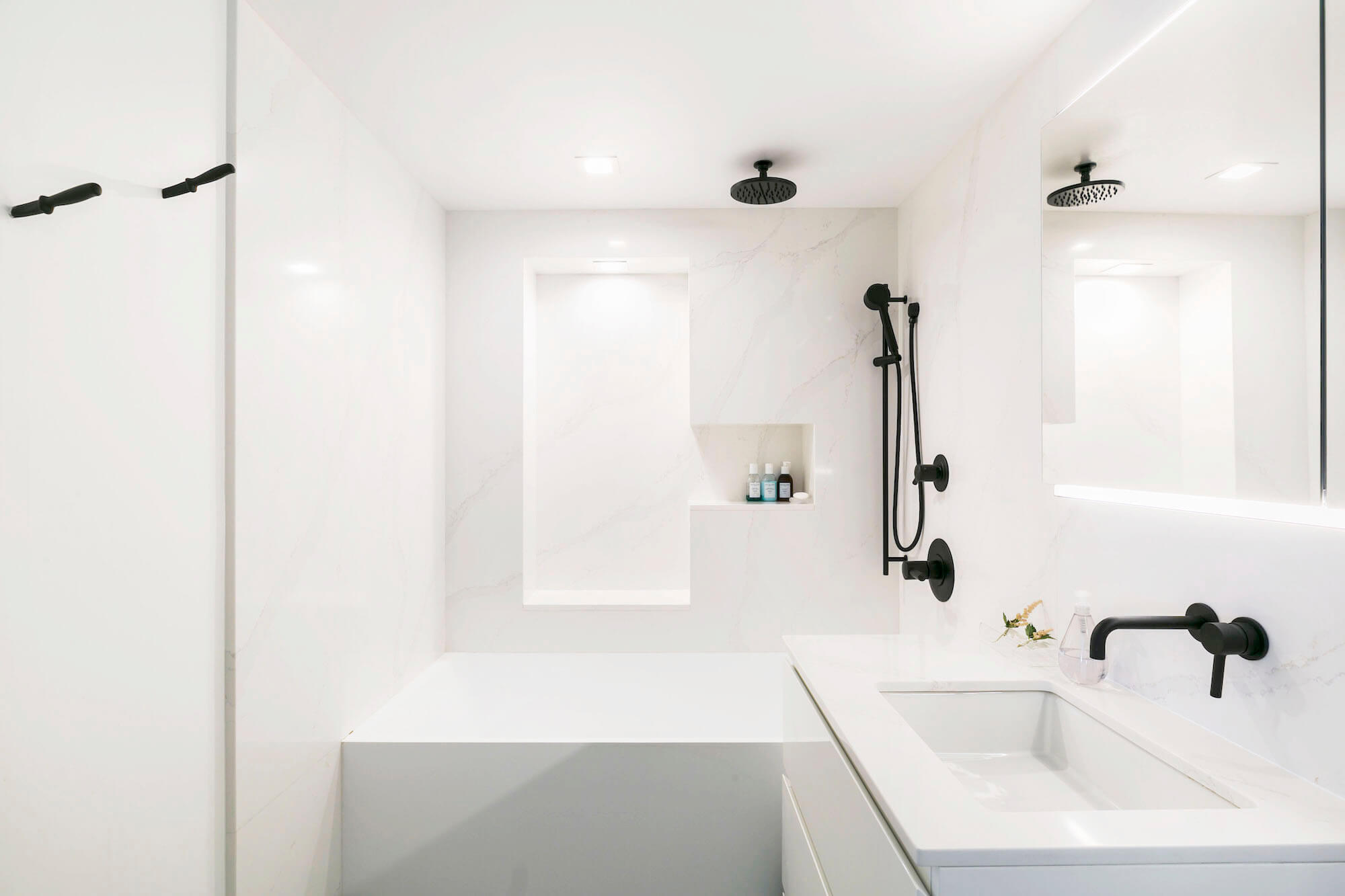 A modern loft bathroom with white marble and black fixtures