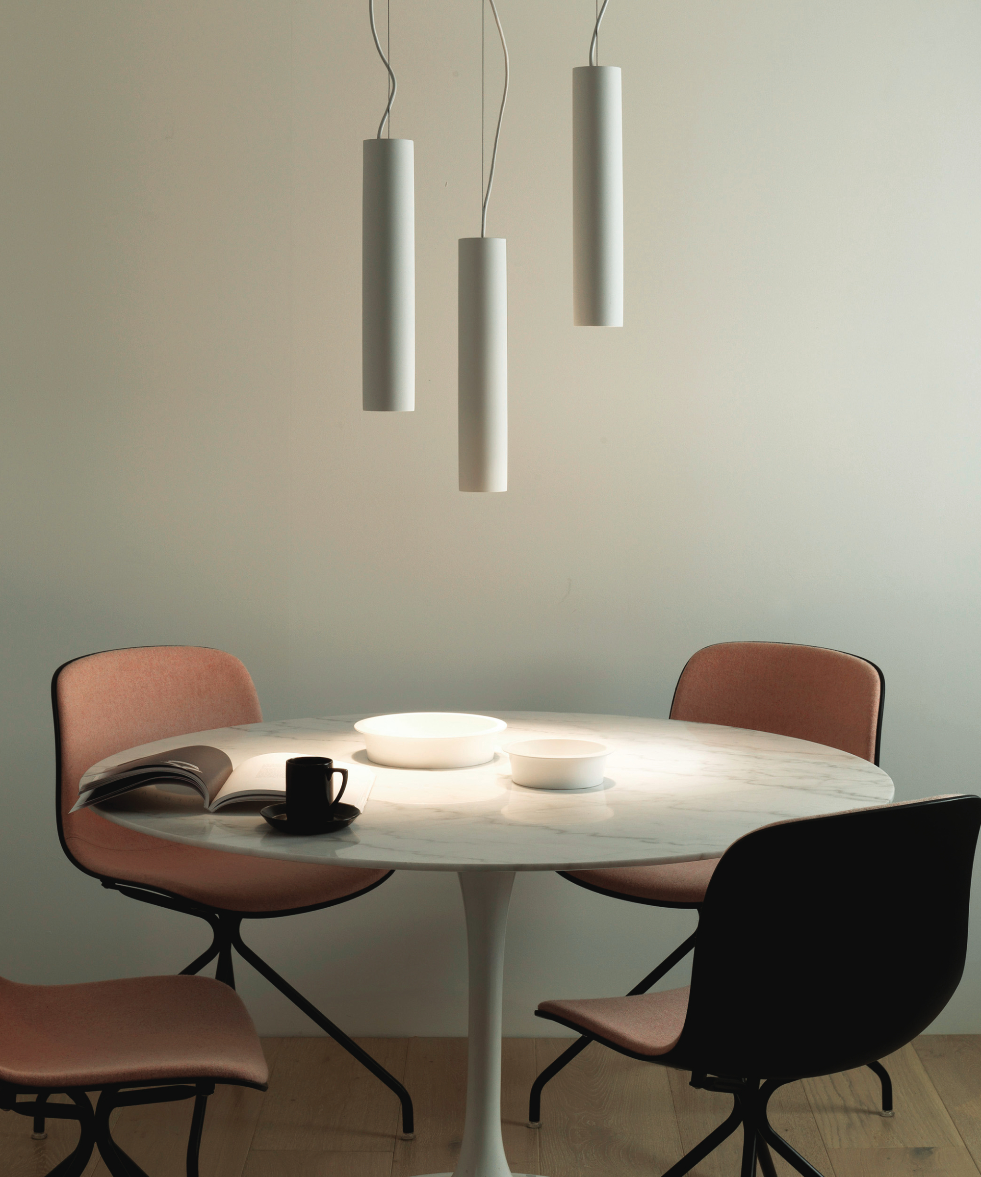 simple three tube white pendant light over round dining table and chairs