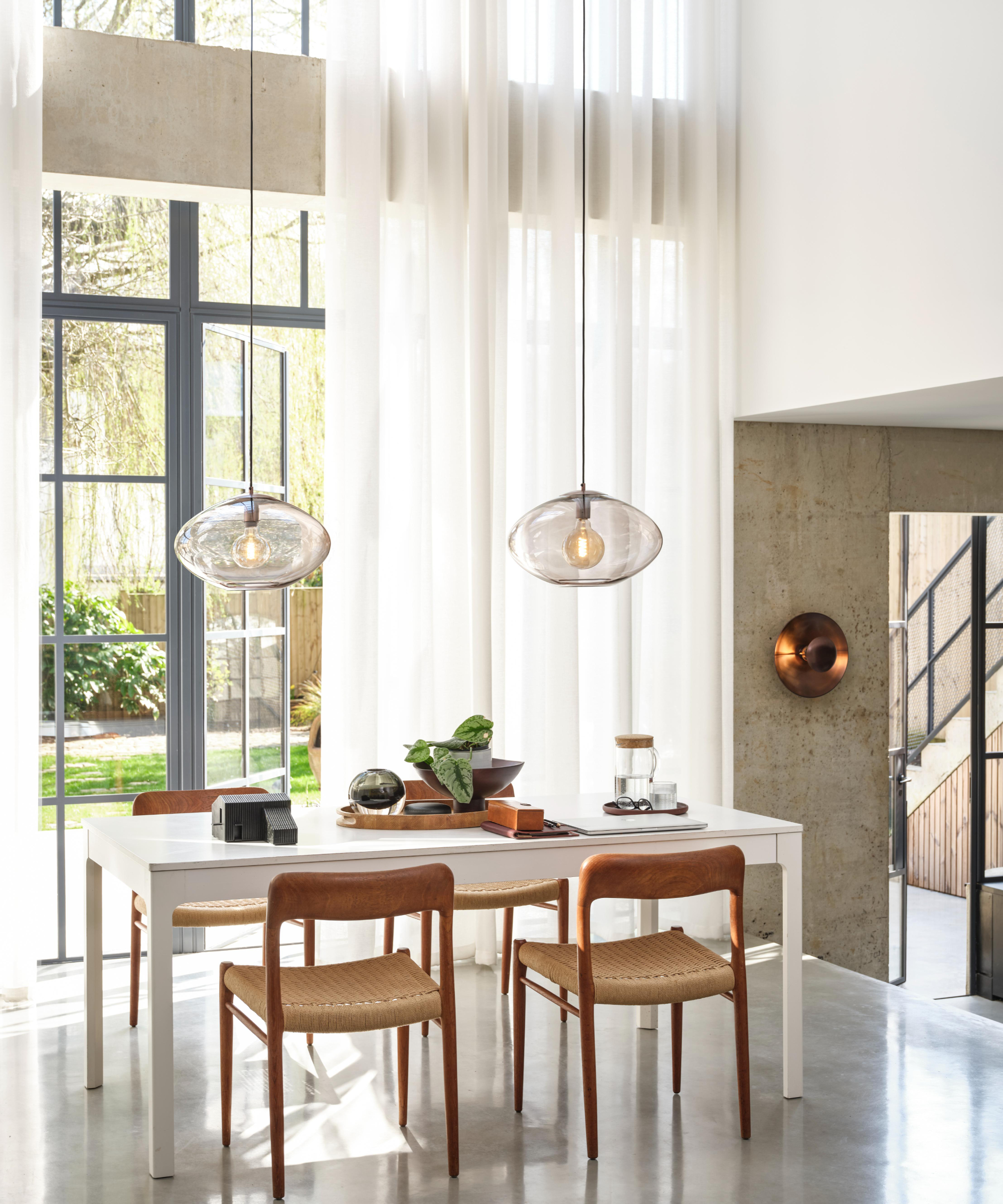 dining room with glass pendant lights above table and modern metal wall sconce on wall near door