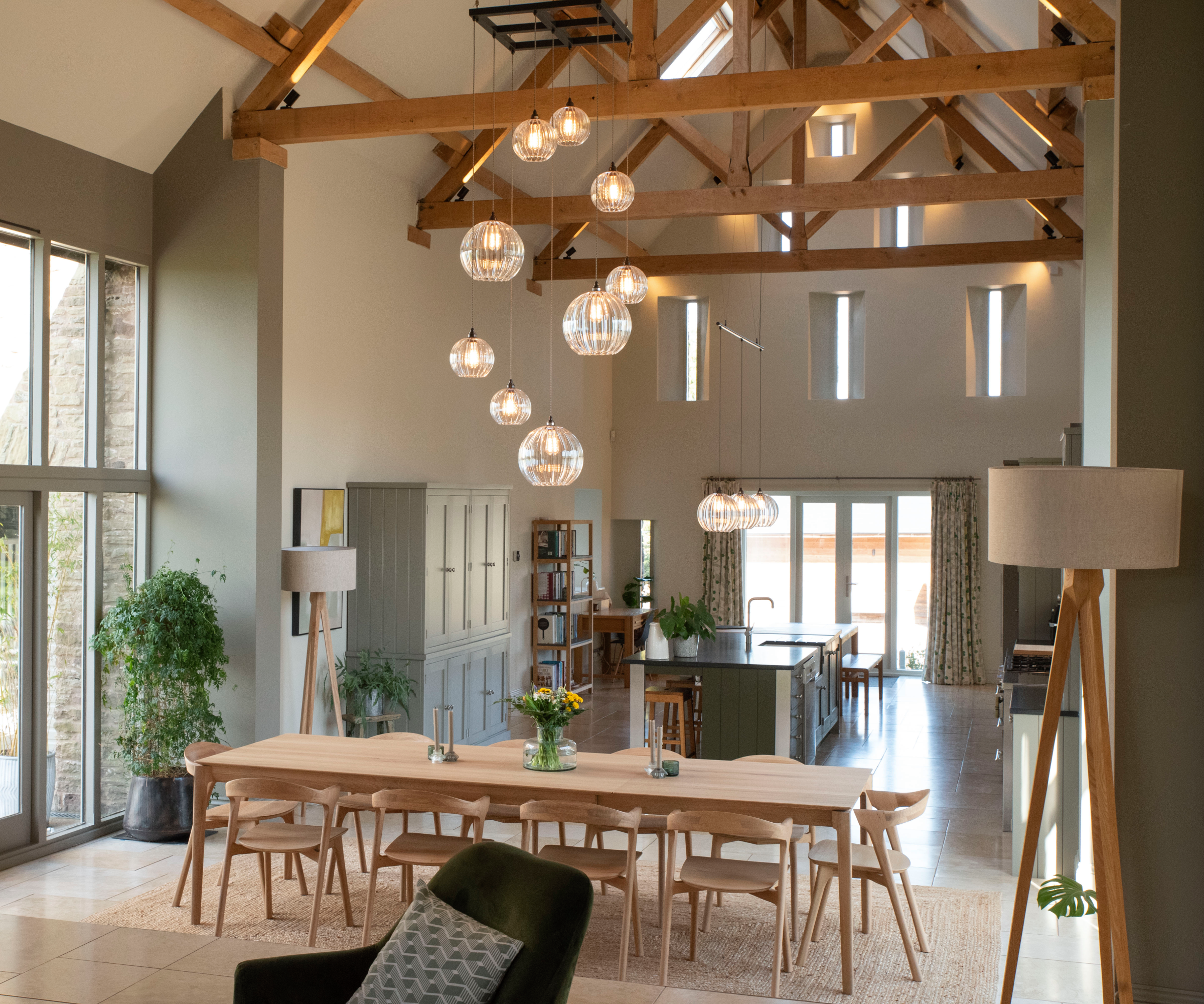 open plan living dining and kitchen space with a variety of glass pendant lights and floor lamps