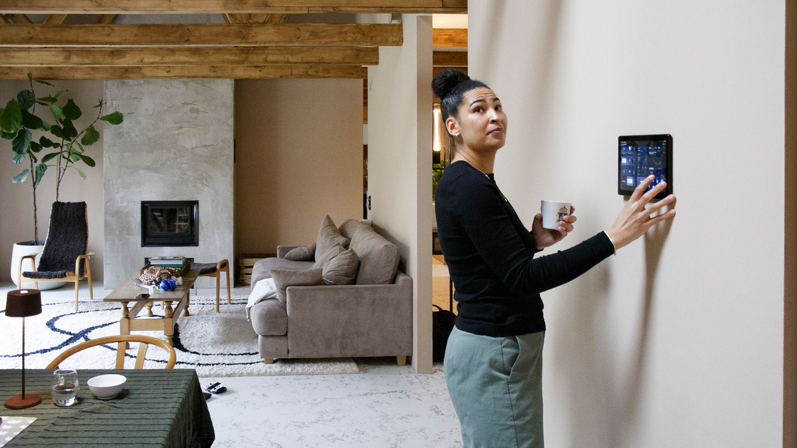 woman adjusting smart heating using a smart hub in modern living room