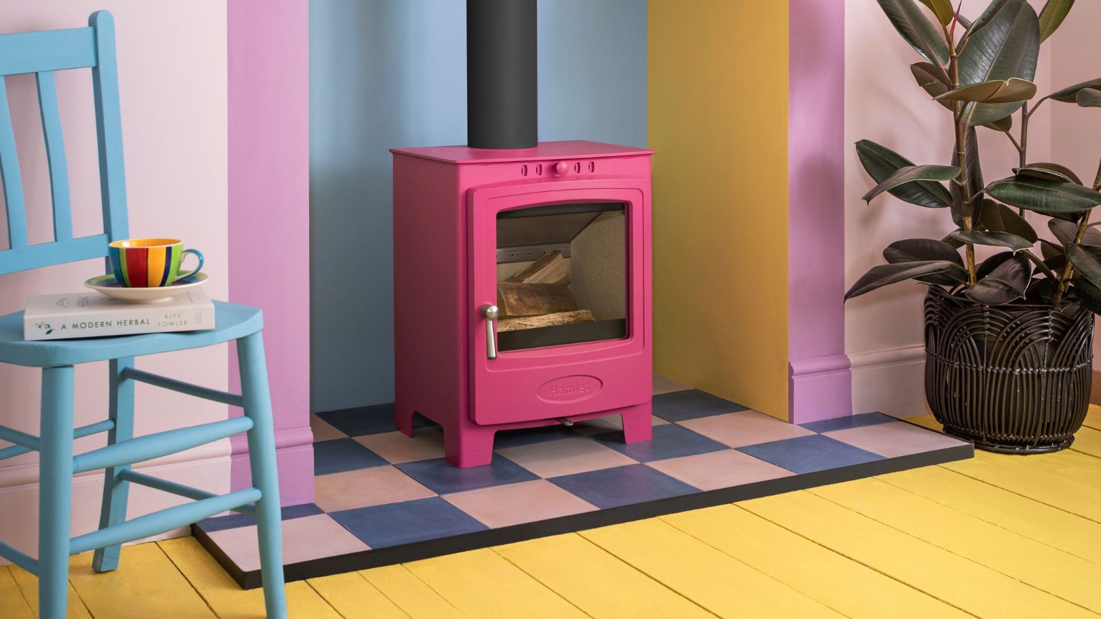 A pink log burner on a chequerboard tile hearth in a vibrant room painted in primary colours