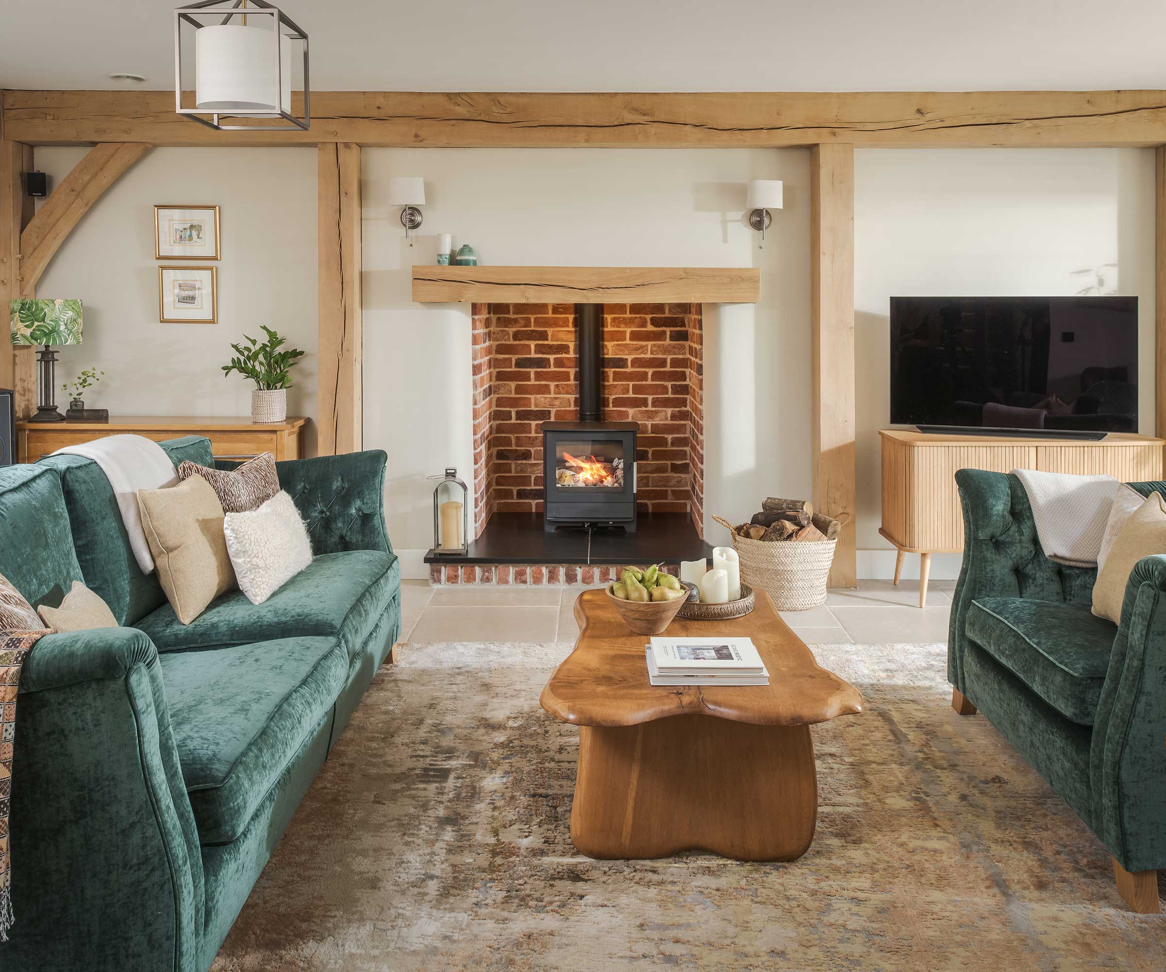 living room in an oak frame house with two blue sofas either side of a log burner