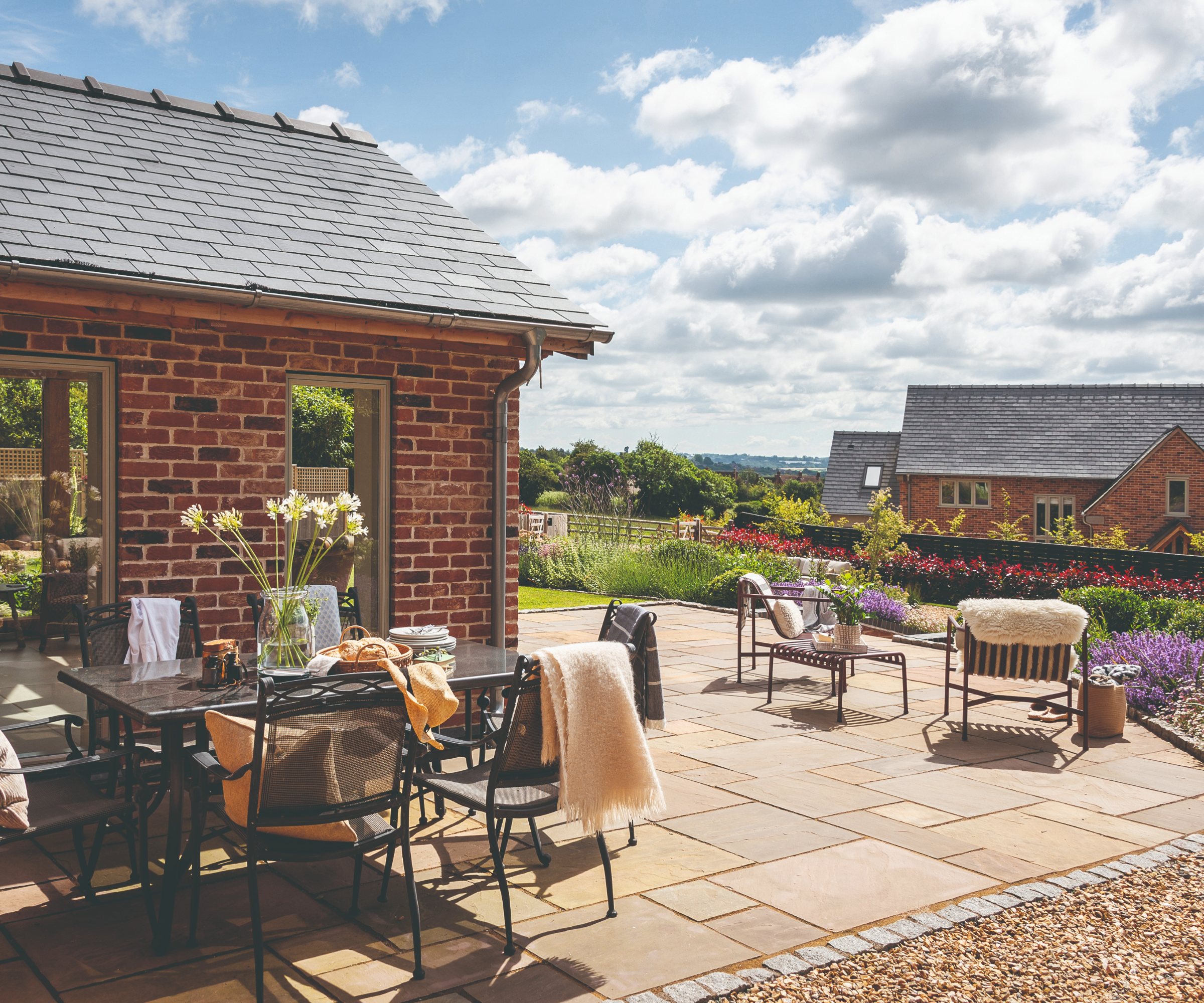 Garden featuring a patio, flower beds, lounge chairs, and an outdoor table and chair set