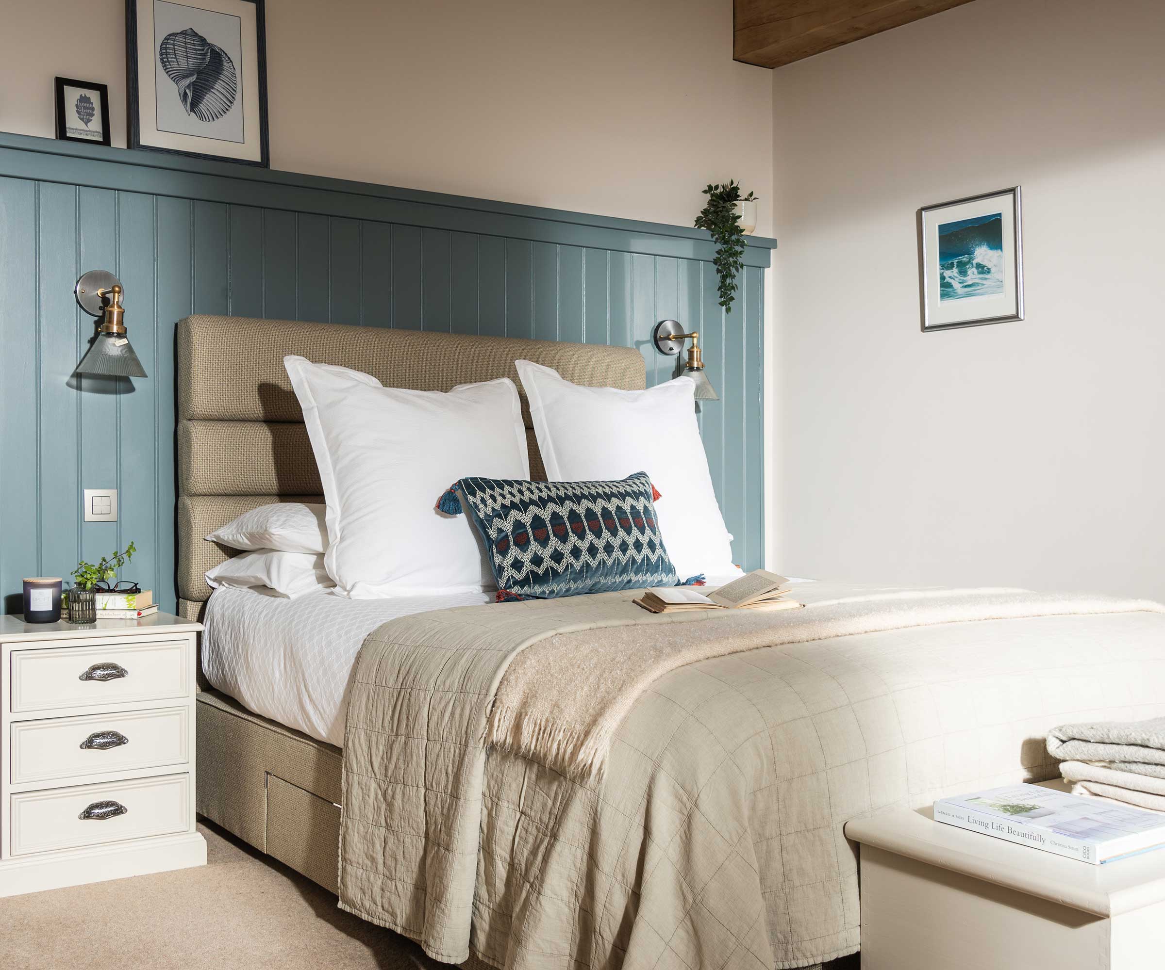 bedroom in an oak frame home with a double bed and blue painted wood panelling behind the bed