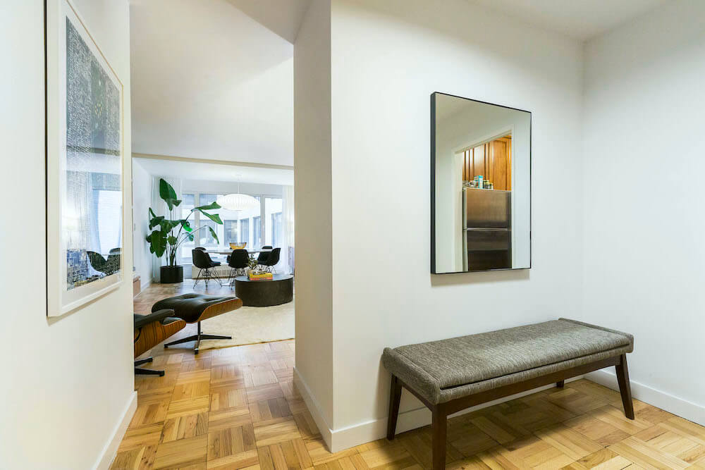 Entryway with mirror and gray upholstered bench