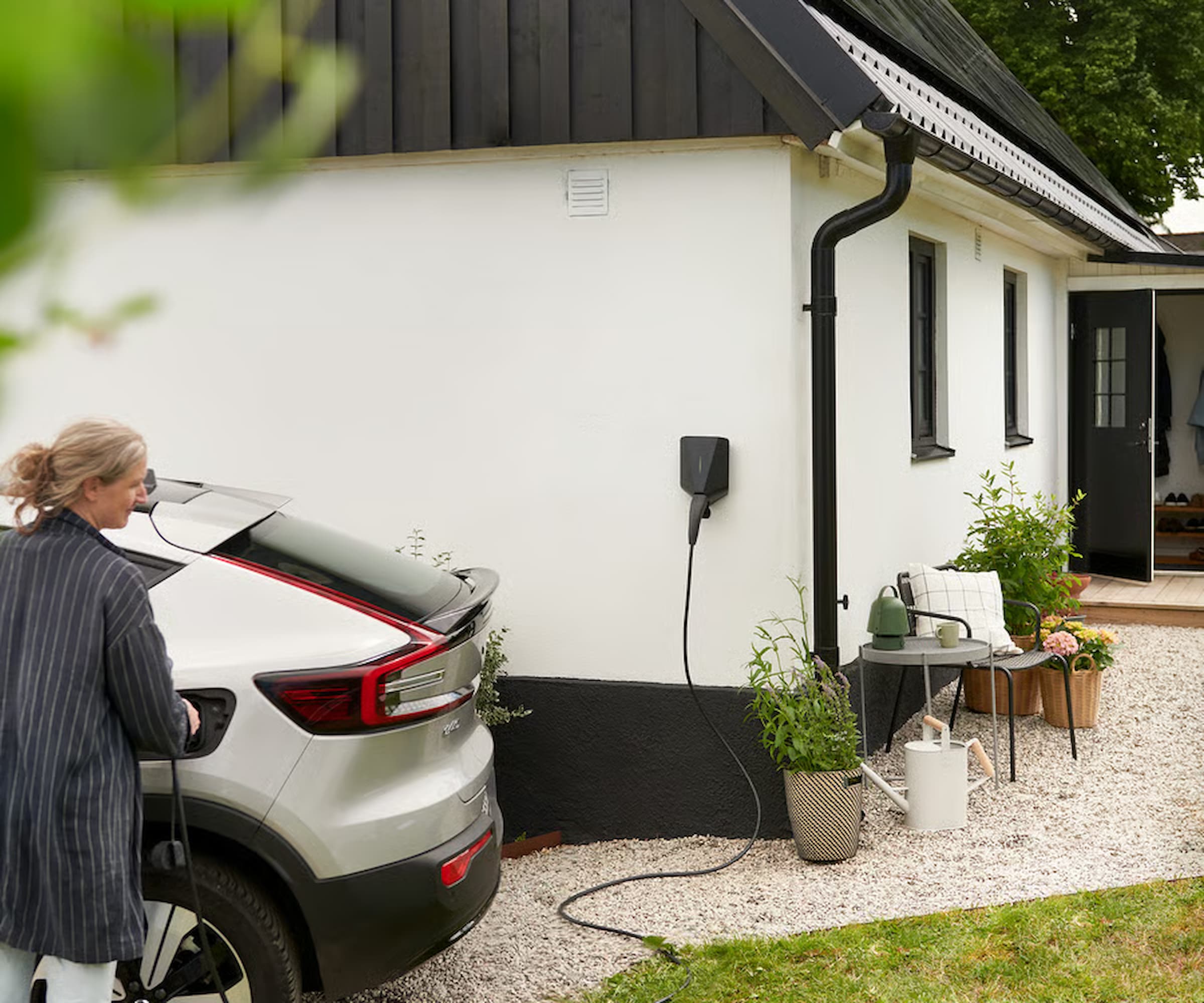 An IKEA EV charger on a white house charging a silver car