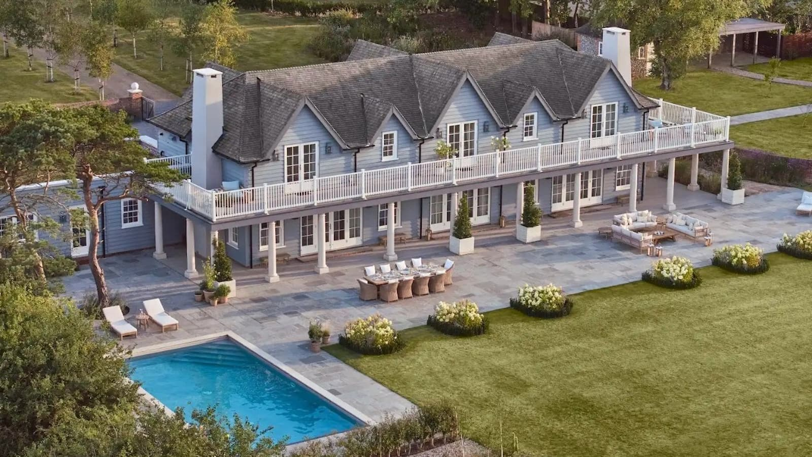 A large house with swimming pool and patio and large gardens along with a full second floor balcony