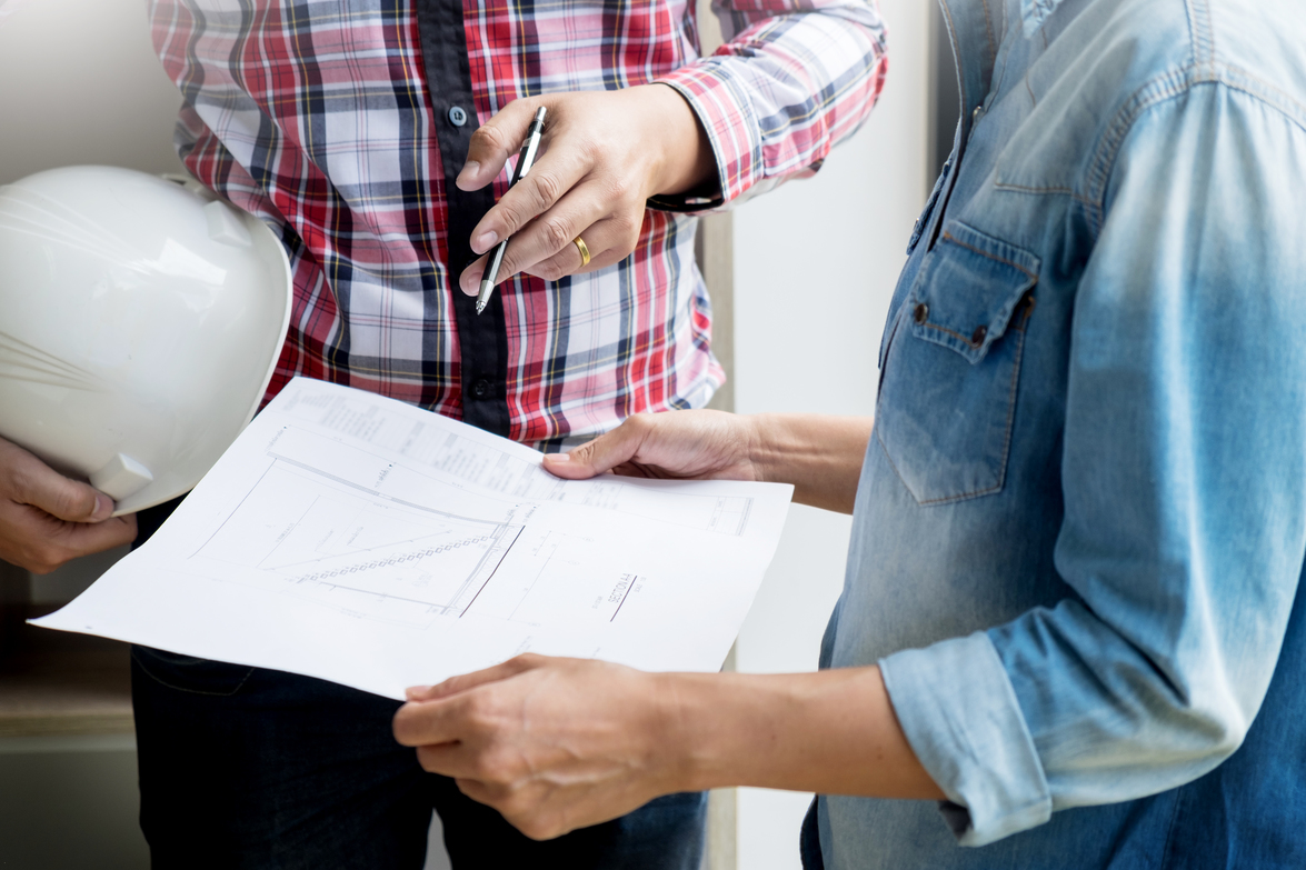 Architects engineer discussing at the table with blueprint - Closeup on hands and project print - to help illustrate What Is Industrial Fabrication