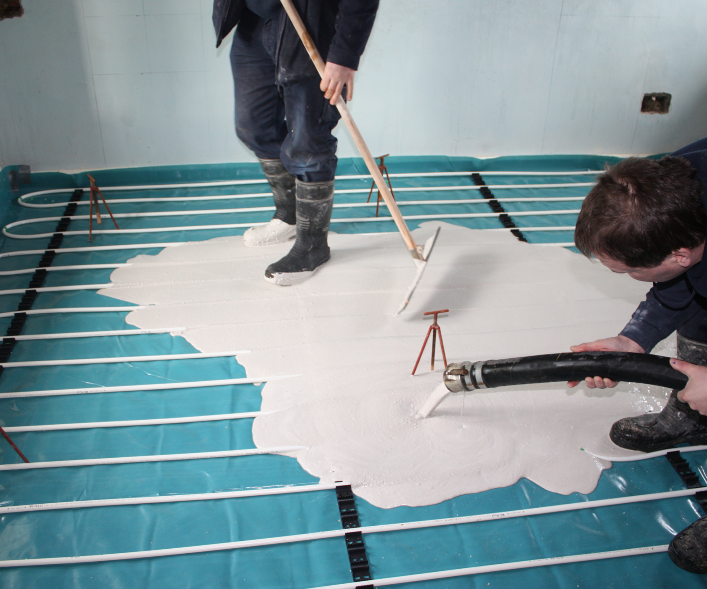 workers pouring screed onto underfloor heating pipes
