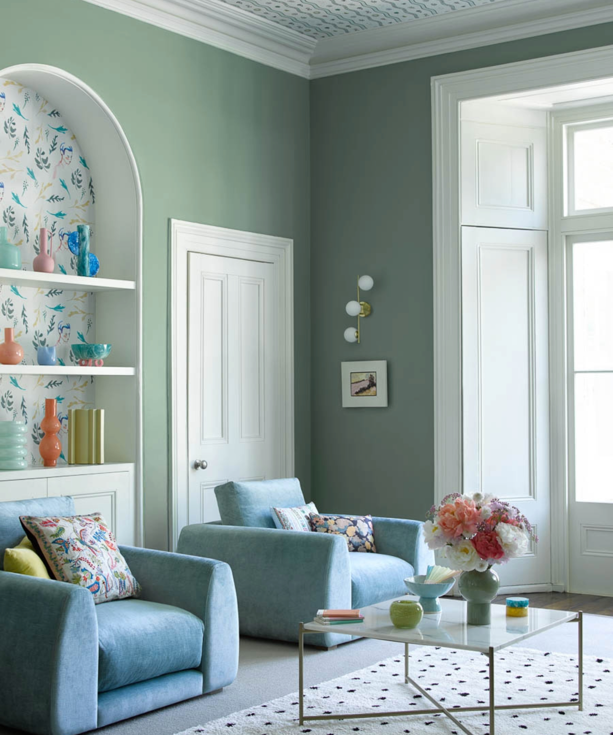 Green living room with blue chairs and arched alcove with shelving