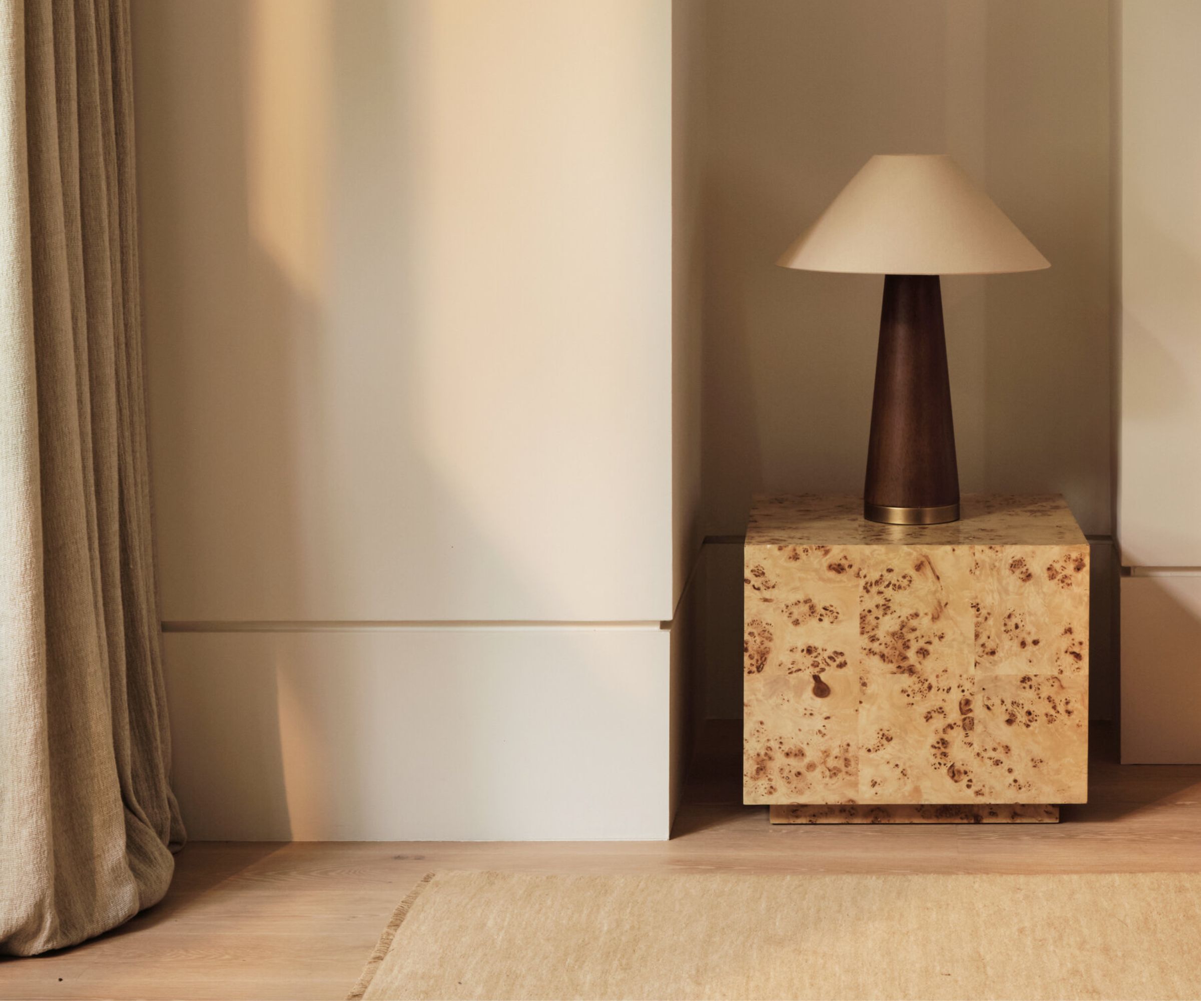 A chic beige bedroom with flush skirting and a mid century bedside lamp on a square bedside table