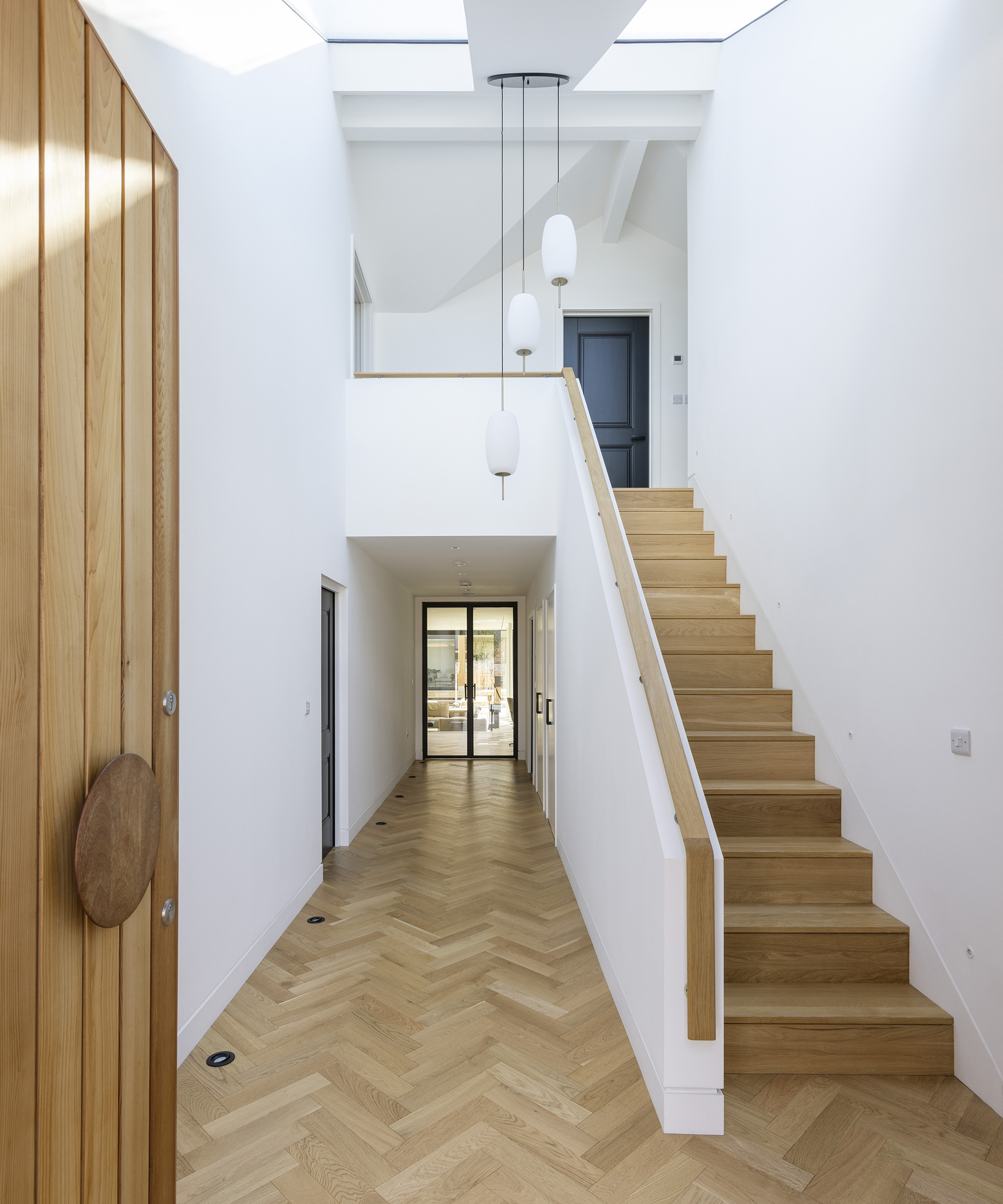 a parquet flooring in a hallway with view up a new staircase to a first floor extension on a bungalow