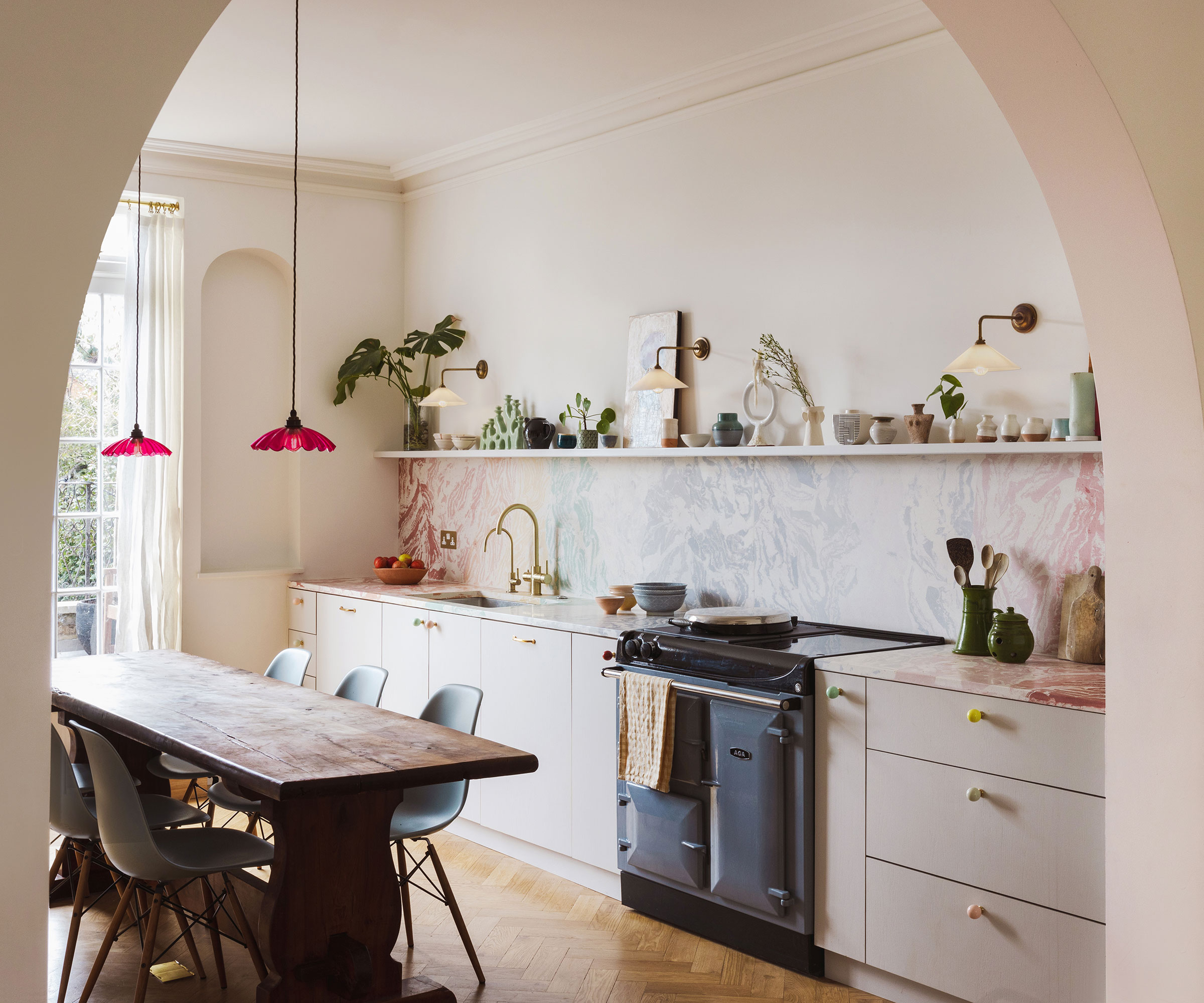 pastel kitchen through archway with pink glass pendant lights and marble splashback