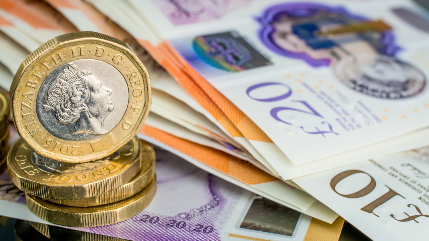 Photo of £10 and £20 notes with four stacked pound coins in the foreground to the left (Image: Dreamstime)